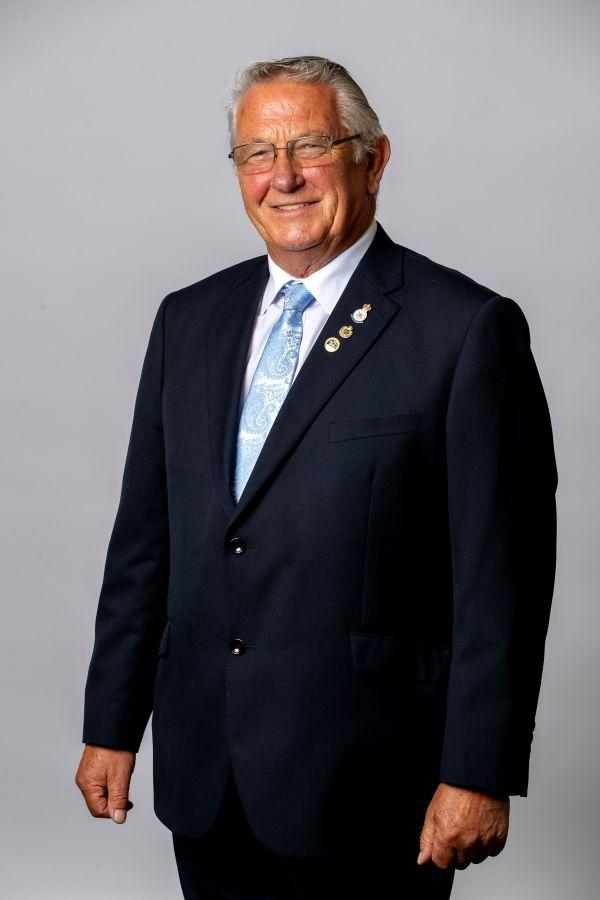 Headshot of Brian Cowie, wearing a smart suit and blue tie