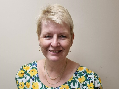 Headshot of Carole Thompson, short blond hair and floral top