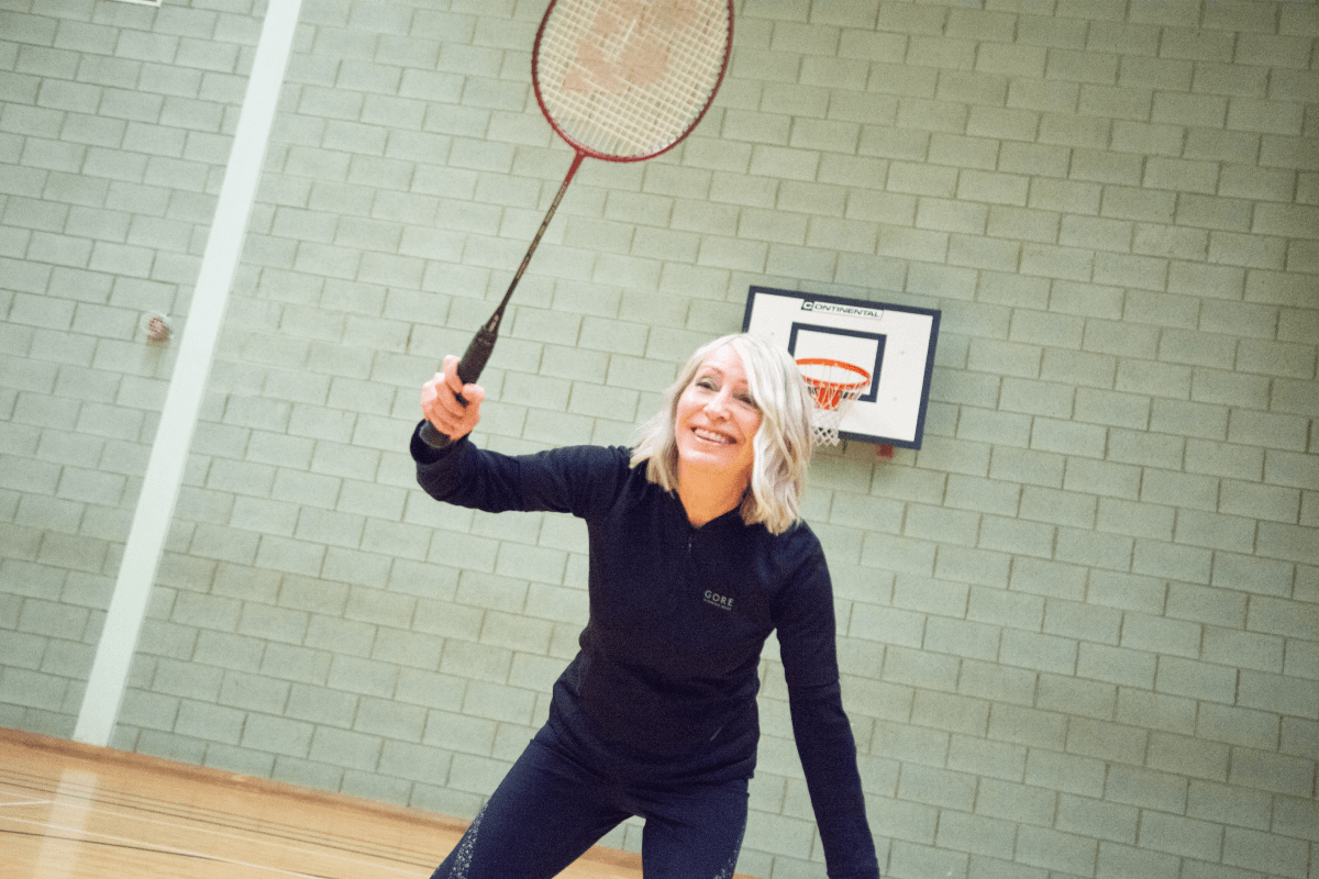 Lady stood in a badminton stance with a racket