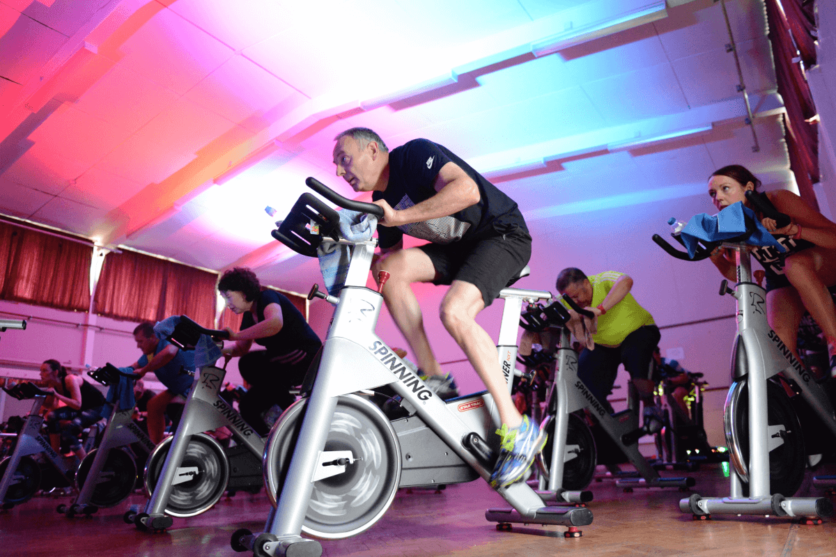 Man partaking in a spin class surrounded by neon lighiting
