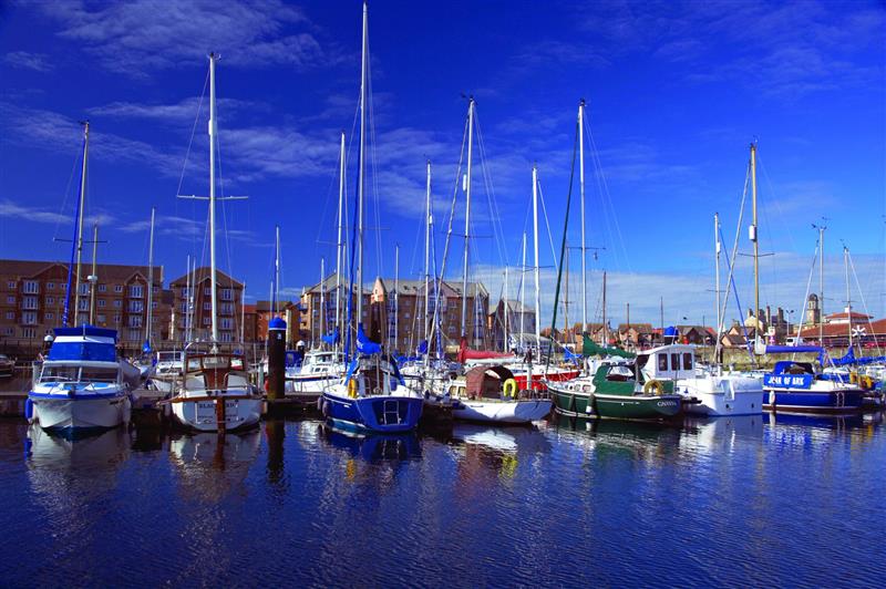Hartlepool Marina with sailboats and yachts docked in calm water, backed by brick buildings under a clear sky