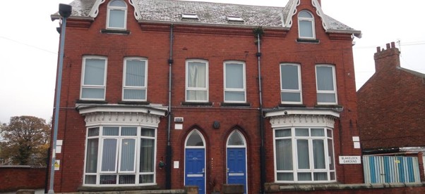 External view of Rose House. Red bricked house with blue doors