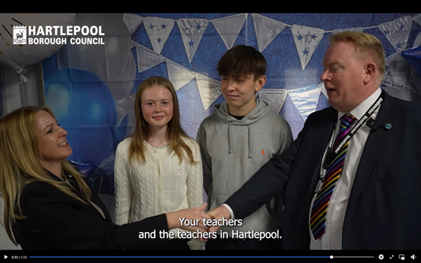 people stood in front of a banner being interviewed on GCSE results day