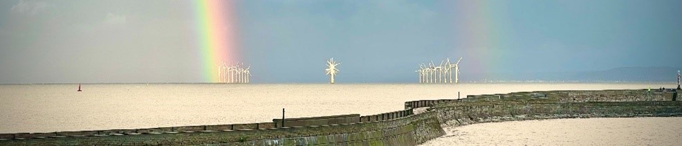 Seafront of Hartlepool showing offshore wind power surrounded by blue skies and rainbow